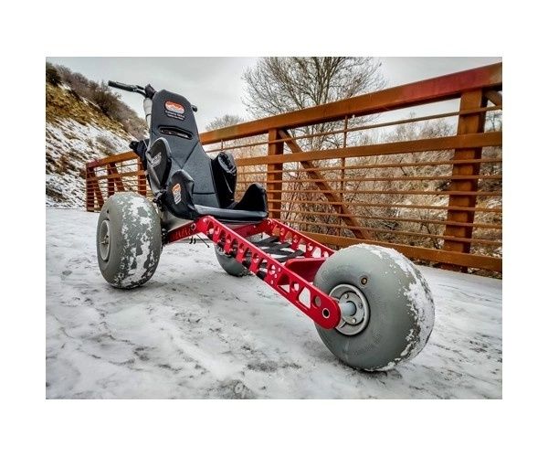 Röd fyrhjulig vagn med snötäckta däck på en isig bro